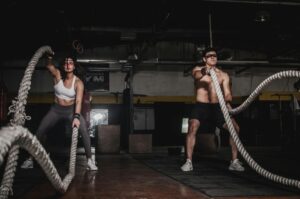 Energetic boy and girl smiling, actively engaged in a rope exercise at a gym, demonstrating fun and effective fitness for a 30 day challenge.